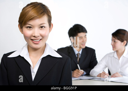 Porträt der jungen Unternehmerin, zwei Geschäftsleute im Hintergrund Stockfoto