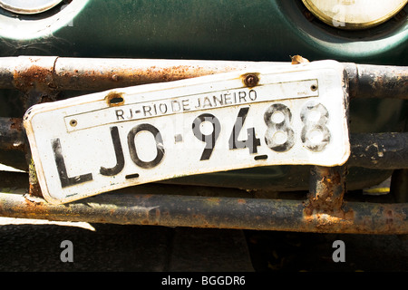 Ein rio de janeiro Nummernschild hängt lose auf dem Rost Stoßstange eines der tausenden von Käfer in Südamerika Stockfoto