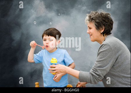 Mittlere gealterte Frau kaukasischen lehrt 3 1/2 Jahre alter Junge Luftblasen durchbrennen. Bild ist Modell veröffentlicht. Stockfoto