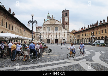 Frauen in Piazza Ducale Vigevano Italien mit 17. Jahrhundert barocke Kathedrale oder Dom entworfen von Antonio da Lonate Radfahren Stockfoto