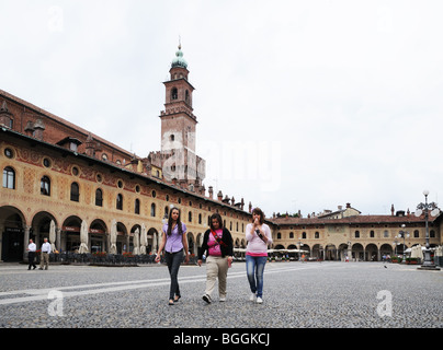 Junge Frauen mit Bramante Turm im Castello Sforzesco in Piazza Ducale Vigevano Lombardei Italien mit Arkaden oder portaci Stockfoto