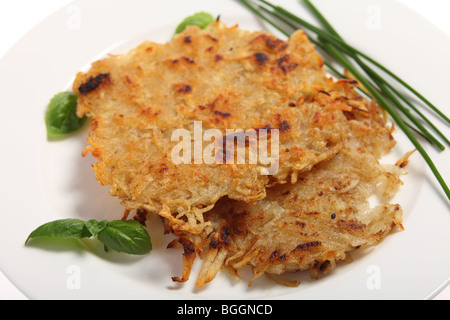 Traditionelle Rösti Kartoffeln im Schweizer Stil, garniert mit Schnittlauch und Basilikum Stockfoto