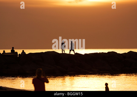 Paare, die auf Wellenbrecher in New Buffalo Michigan in der Abenddämmerung Stockfoto