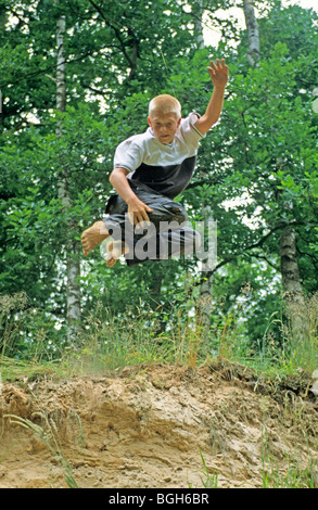 Junge, springen von einer Sanddüne Stockfoto