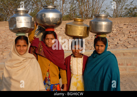 4 (vier) Rajasthani Mädchen Carring Wasser Krüge auf dem Kopf auf ihrem Weg in das Dorf gut Blick in die Kamera Stockfoto