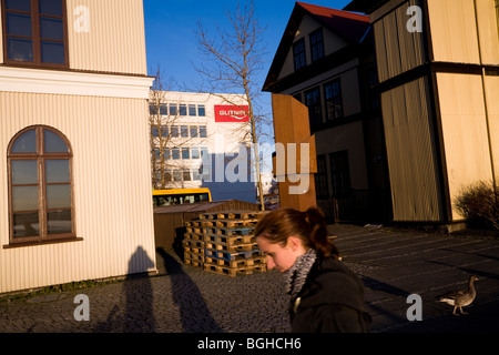 Ein Mädchen zu Fuß auf einem sonnigen Herbstnachmittag, Glitnir Bank im Hintergrund. Die Innenstadt von Reykjavik, Island. Stockfoto