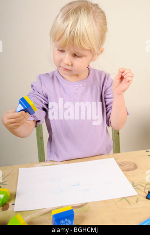 Stock Foto von einem vier Jahre alten Mädchen mit Tinte Stempel während einer Sitzung kreatives Spielen. Stockfoto