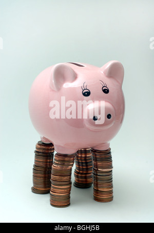 SPARSCHWEIN, SPARSCHWEINE STEHEN AUF PFÄHLEN DER BRITISCHEN MÜNZEN WIEDER DIE WIRTSCHAFT EINSPARUNGEN EINKOMMEN REZESSION BANKEN CASH LÖHNE UK Stockfoto