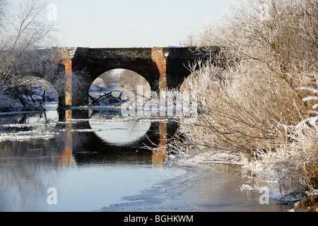 Dorf Holt, Wales. Malerische Aussicht auf das 14. Jahrhundert mittelalterliche Holt Brücke über den Fluss Dee an verschneiten Wintertag. Stockfoto