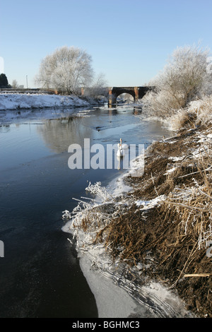 Dorf Holt, Wales. Malerische Aussicht auf den Fluss Dee auf einen kalten, verschneiten Wintertag mit Holt Brücke im Hintergrund. Stockfoto