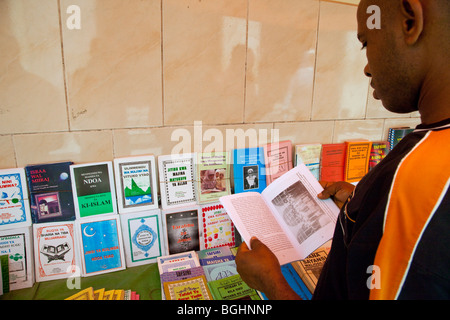 Sansibar, Tansania.  Kunden wird ein Buch in einem Buchständer, Verkauf von Büchern über den Islam in Swahili oder Arabisch untersucht. Stockfoto