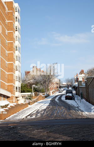 Schneebedeckte Straße in Brighton mit Glatteis und Schnee bedeckten Autos und Bürgersteige zusammen mit Matsch bedeckt Straßen. Stockfoto