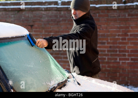 Mann mit Eiskratzer auf Auto Windschutzscheibe Stockfoto