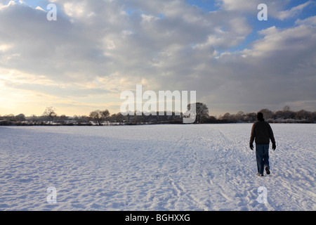 Mann geht im Winterschnee in Tolworth Court Farm Nature Reserve, Kingston, Surrey, England, UK. Januar 2010 Stockfoto