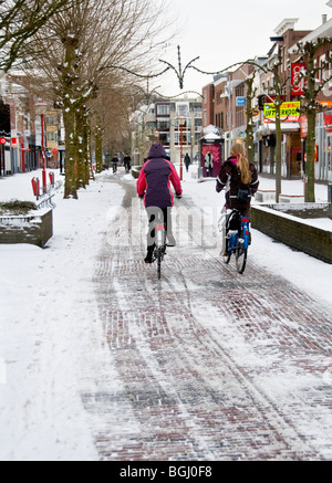 Zwei Radfahrer, die ihren Weg durch die verschneiten Haupteinkaufs-Straße in die niederländische Stadt Veenendaal Stockfoto