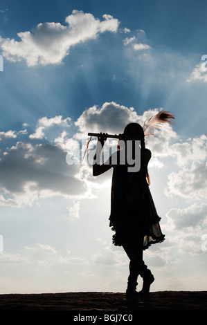 Inderin in Krishna Silhouette-Pose bei Sonnenuntergang in der indischen Landschaft Stockfoto