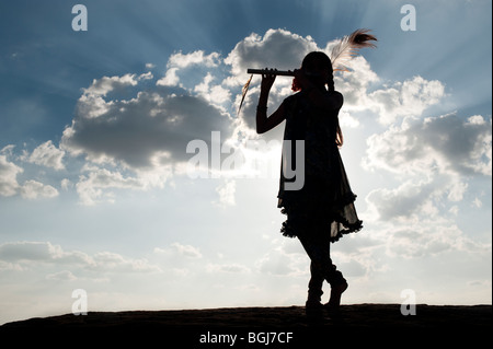 Inderin in Krishna Silhouette-Pose bei Sonnenuntergang in der indischen Landschaft Stockfoto