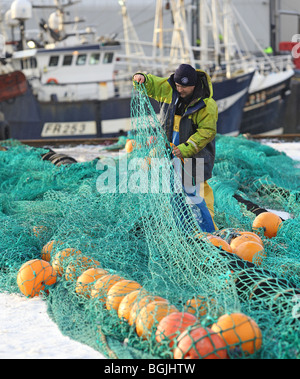 Fischer tragen wasserdichten Oilskins ausbessern Netze im Schnee an der Fischerei Dorf von Fraserburgh, Aberdeenshire, Schottland, Großbritannien Stockfoto