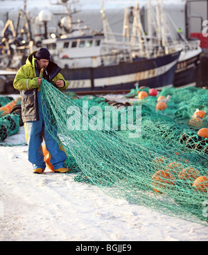 Fischer tragen wasserdichten Oilskins ausbessern Netze im Schnee an der Fischerei Dorf von Fraserburgh, Aberdeenshire, Schottland, Großbritannien Stockfoto