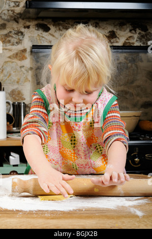 Stock Foto von einem vier Jahre alten Mädchen mit einem Nudelholz um zu die Cookie-Mischung zu glätten, bevor sie einige Kekse macht. Stockfoto