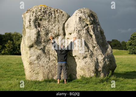 Mann berühren einen großen Felsblock, ausgestreckten Armen Stein Kreis, Avebury, Wiltshire, England, Großbritannien, Europa Stockfoto