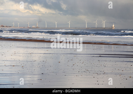 Eine Reihe von Windenergieanlagen auf den Hafen an der Wand befestigt und gesehen in feuchten Sand in Blyth, Northumberland, England, UK wider Stockfoto