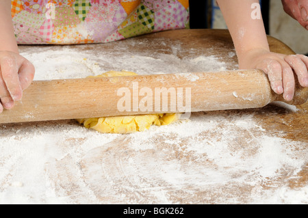 Stock Foto von einem vier Jahre alten Mädchen mit einem Nudelholz um zu die Cookie-Mischung zu glätten, bevor sie einige Kekse macht. Stockfoto