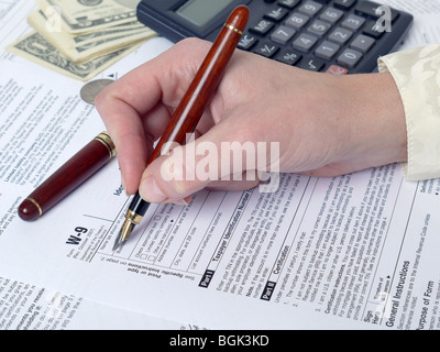 Weibliche Hand Ausfüllen der Einkommensteuererklärung des w-9 mit Stift Stockfoto