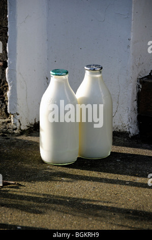 Zwei volle Milchflaschen vor der Haustür, eine grüne Oberseite und eine silberne Zero Waste Stockfoto