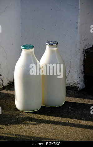 Zwei volle Pint Flaschen Milch vor der Haustür, eine grüne Oberseite und eine silberne Null Abfall Stockfoto