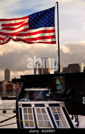 Amerikanische Flagge, die vom Heck der USS Constitution mit den Gebäuden der Innenstadt von Boston über, Massachusetts, USA Stockfoto