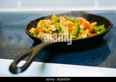 Chicken Fajitas in einer eisernen Pfanne auf einem Herd kochen. Stockfoto