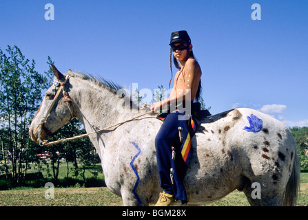 Blackfeet Teenager gekleidet in Mitte 1800 Ornat mit Kavallerie Hut sitzt auf ein Appaloosa Pferd in Browning Montana bareback Stockfoto