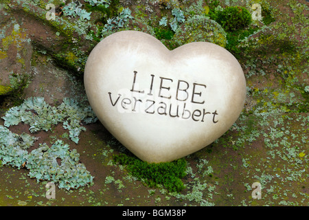 Herz aus Stein mit den Worten "Liebe Verzaubert", Deutsch für "Liebe verzaubert" Stockfoto
