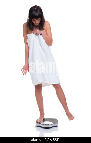 Eine Frau in ein Handtuch mit einem Gewicht von selbst gewickelt und versuchen zu betrügen die Waage, isoliert auf weißem Hintergrund. Stockfoto