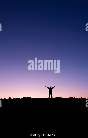 Silhouette eines Mannes, der seine Hände in den Sonnenaufgang nach der Eroberung eines Gipfels Stockfoto