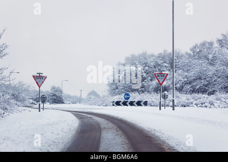 Aufnahme einer Straße auf dem Ansatz zu einem Kreisverkehr nach einem schweren Schneefall, Zeichen Vorfahrt Stockfoto