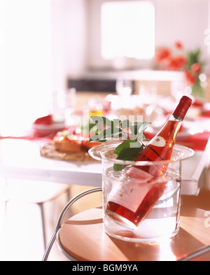 Rose Wein Flasche in Wasser mit Pflanze Blatt Stockfoto