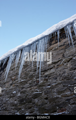Eiszapfen hängen von Dachrinnen Stockfoto
