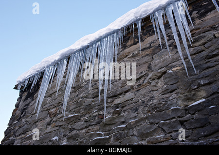 Eiszapfen hängen von Dachrinnen Stockfoto
