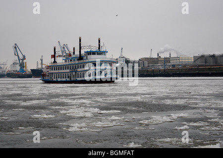 Ein Raddampfer mit Eiszapfen am Steuer ist im Hafen von Hamburg auf den zugefrorenen Fluss "Elbe" abgebildet. Stockfoto