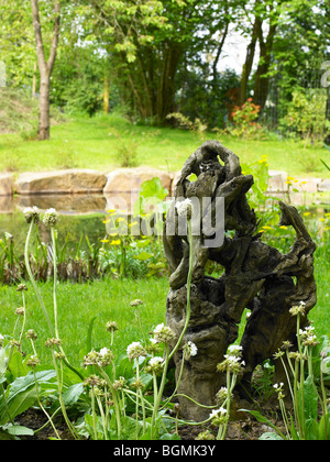 Ein Stück Treibholz in einem Garten mit einem Teich im Hintergrund Stockfoto