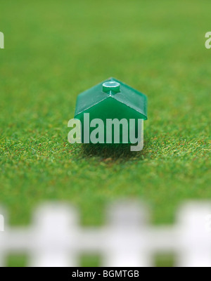 Monopol-Haus auf dem grünen Rasen mit weißen Lattenzaun. Stockfoto
