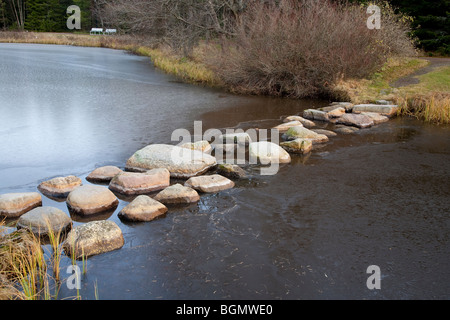 Steine über einen gefrorenen Gartenteich zu treten, Finnland Stockfoto