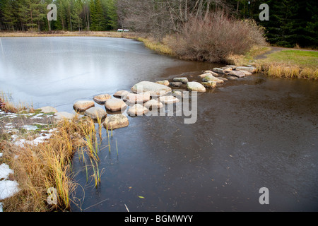 Steine über einen gefrorenen Gartenteich zu treten, Finnland Stockfoto