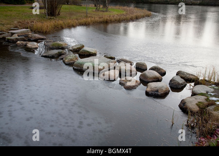 Steine über einen gefrorenen Gartenteich zu treten, Finnland Stockfoto