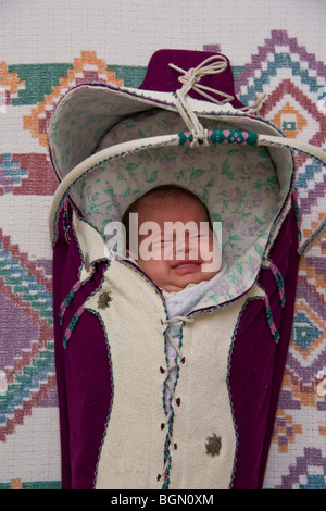 Neugeborenes Kind weint gebündelt und verpackt in einem traditionellen Kindertrage Stockfoto