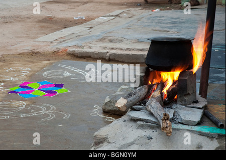 Kochendes Wasser auf offenem Feuer in einem ländlichen indischen Dorf vor einem Rangoli design während des Festivals von sankranthi. Andhra Pradesh, Indien Stockfoto