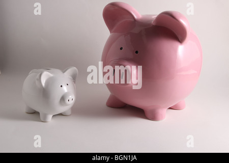Zwei Spardosen. Eine große rosa Sparschwein und eine kleine weiße piggy Bank Stockfoto
