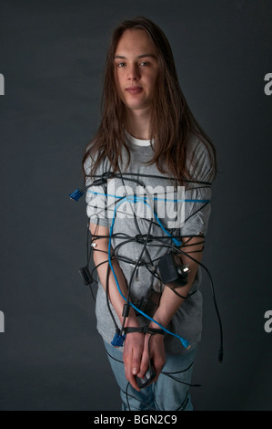 Teenager mit langen Haaren, die mit Computer-Kabel gefesselt Stockfoto